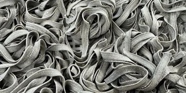 Close-up of uncooked gray pasta noodles scattered densely.
