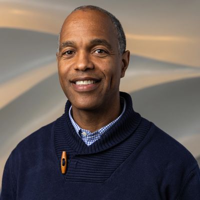 Smiling man in a navy sweater with a button.