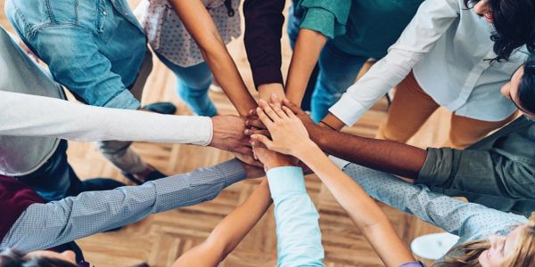 Group joining hands in teamwork gesture.