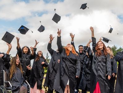 Graduates throwing caps in celebration outdoors.