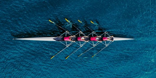 A rowing team of four rowing on blue water.