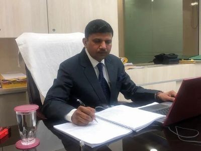 A man in a suit working at a desk with documents and a laptop.