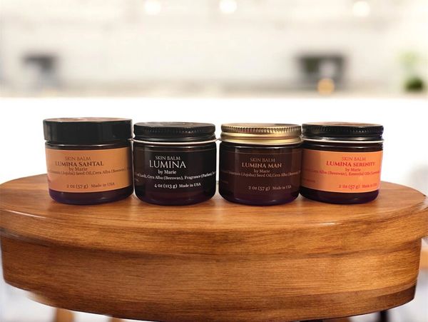 Four jars of Lumina skin balm arranged on a wooden surface.