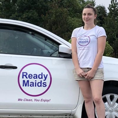 Three people standing beside a white car and wearing shirts with the logo of readymaidsusa.com