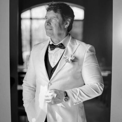 Nico in a white suit smiling