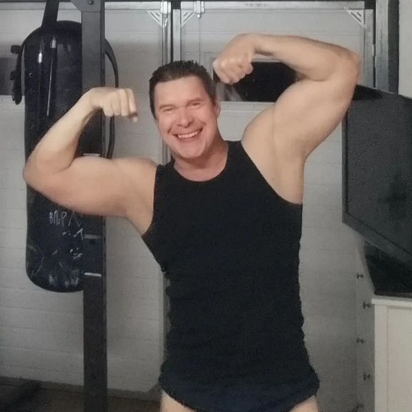 Nico in a black fitness outfit smiling and double biceps posing