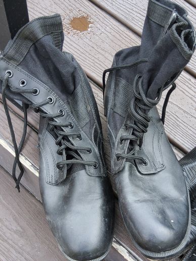 Pair of black combat boots on wooden surface.