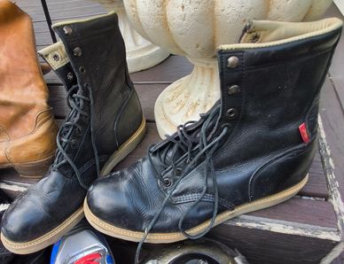 Black leather boots with laces on a wooden surface.