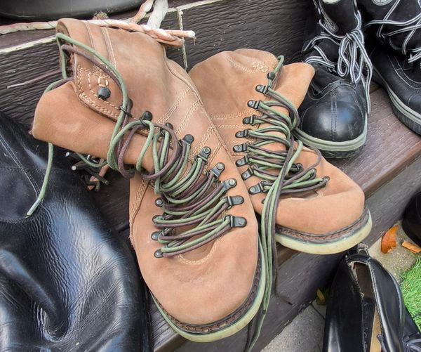 Pair of worn brown boots with green laces.