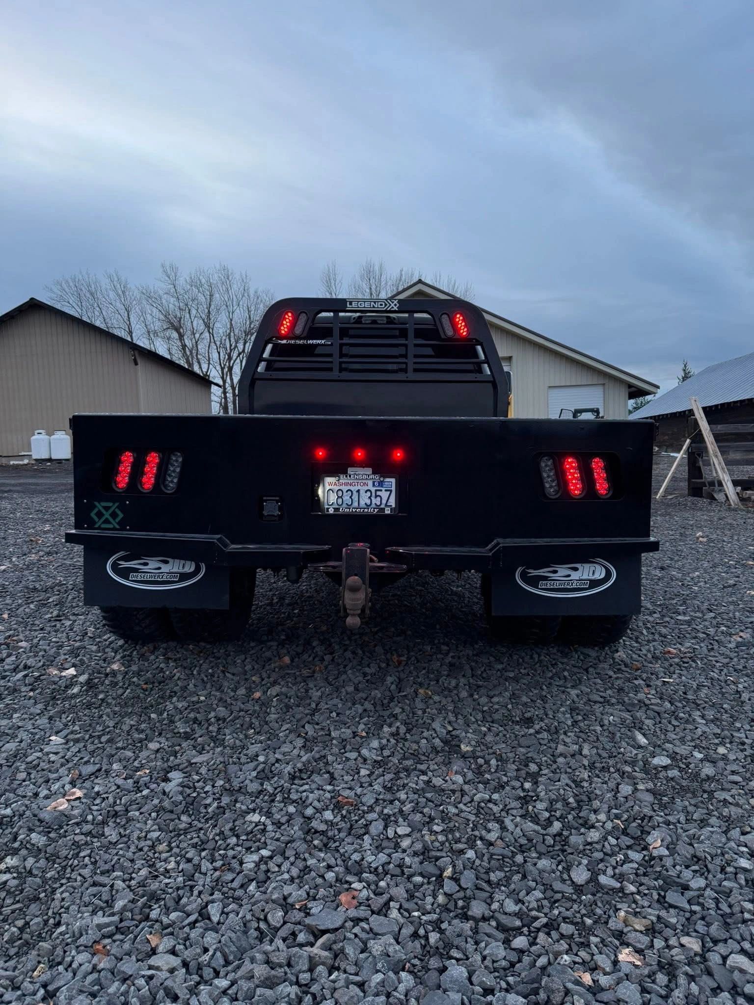 Rear view of a flatbed truck with illuminated tail lights.