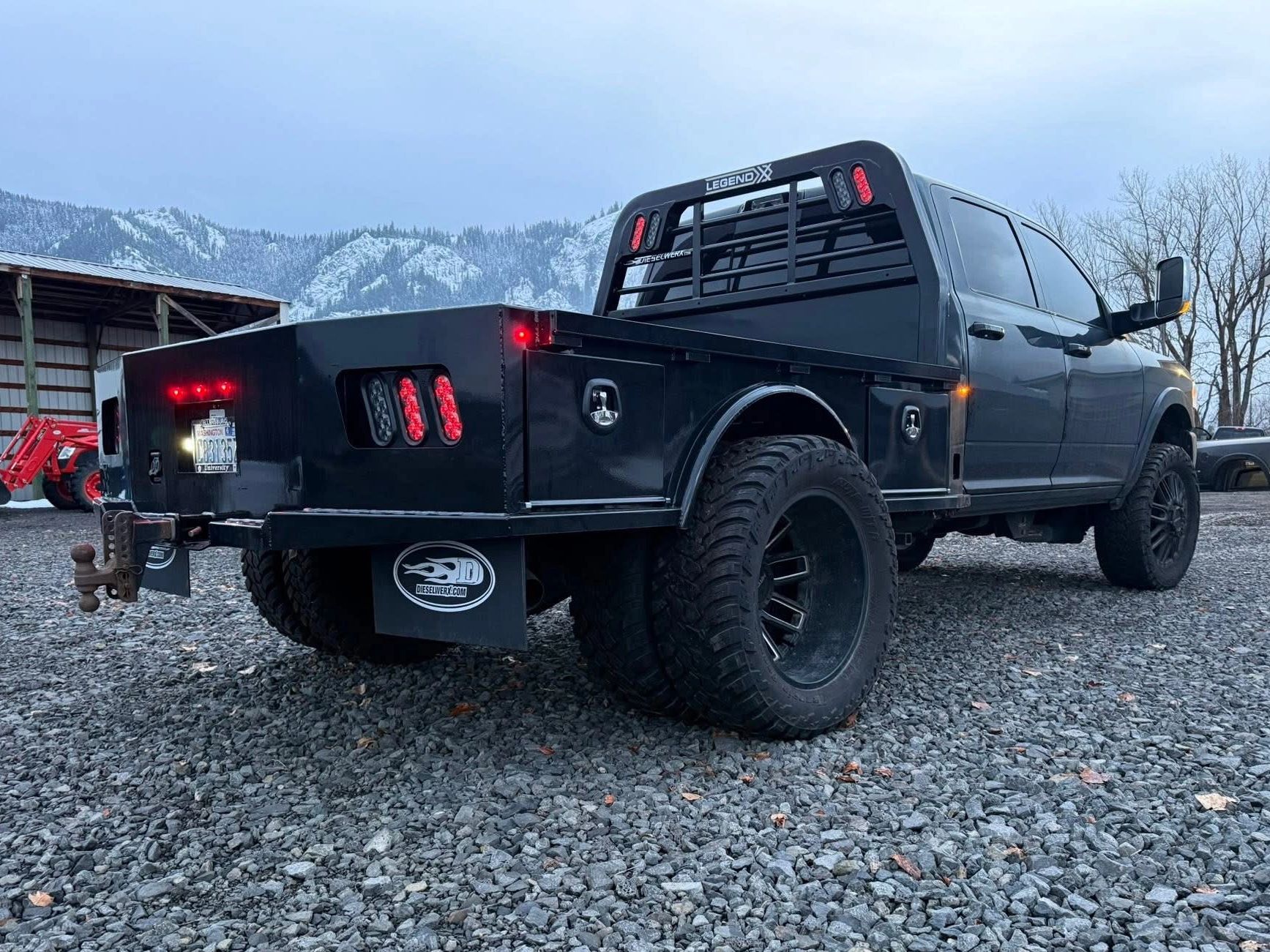 Black truck with flatbed and mountain backdrop.