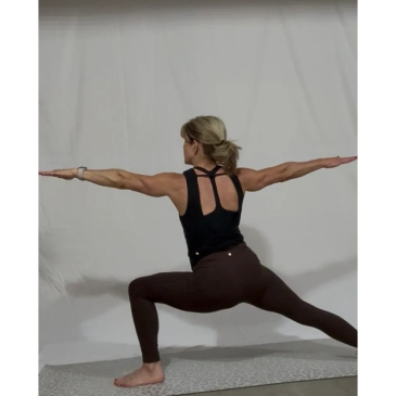 Woman doing yoga warrior pose indoors.