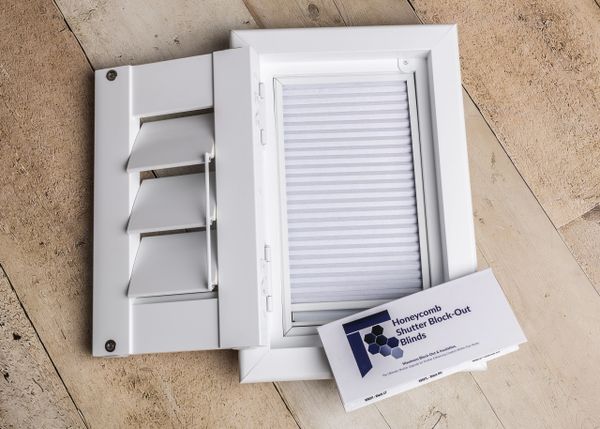 White honeycomb shutter block-out blinds on wooden floor.