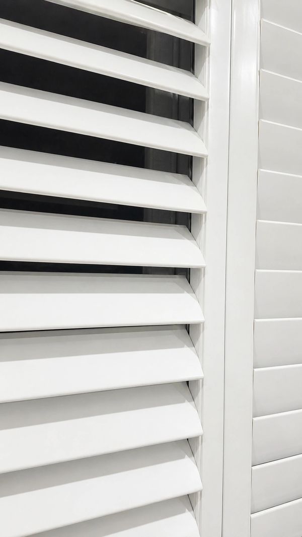 Close-up of white window shutters with angled slats.