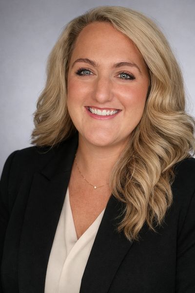 Professional woman with blonde hair smiling in a business portrait.