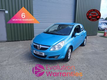 Blue Vauxhall car parked outside a garage with warranty logos.