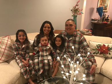 Family in matching plaid pajamas sitting on a couch.