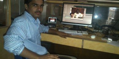 A man sitting at a desk with a computer and a small device showing a similar image on screen.