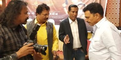 Four men engaged in a discussion, one holding a camera.