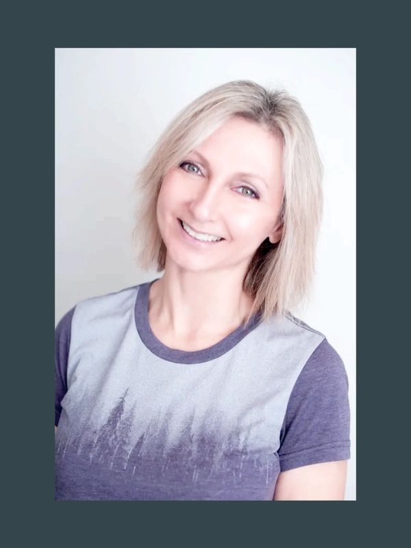Smiling woman with blonde hair wearing a purple and gray t-shirt.