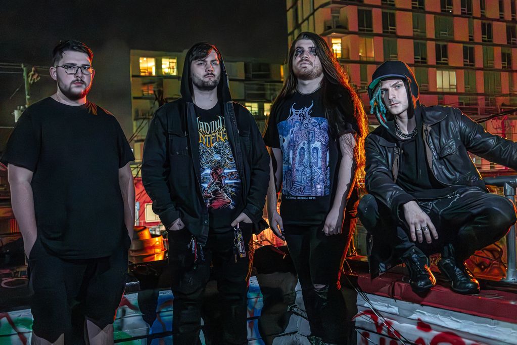 Group of four young men posing with a cityscape at night.