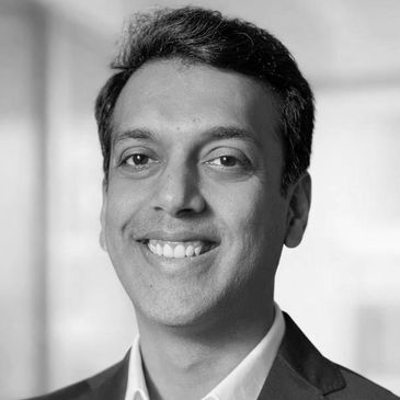 Black and white portrait of a smiling man in a suit.