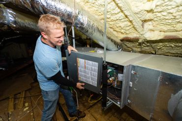 Man inspecting HVAC unit in attic.
