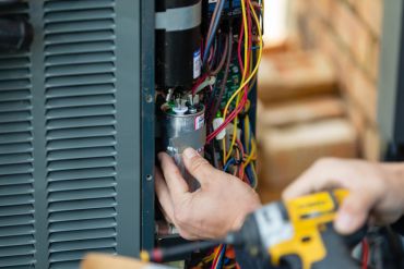 Technician repairing HVAC unit wiring.