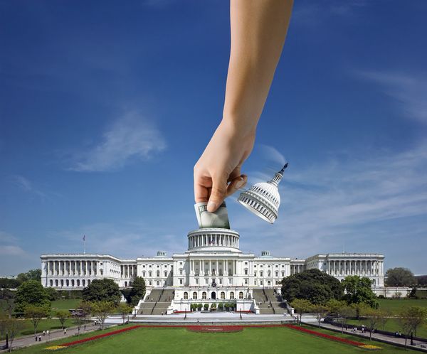 A giant hand placing the Capitol dome like a coin into the building.