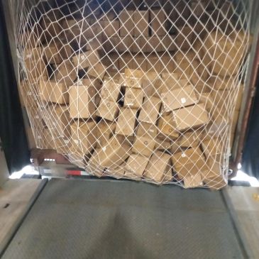 Boxes stacked and secured with netting inside a cargo area.