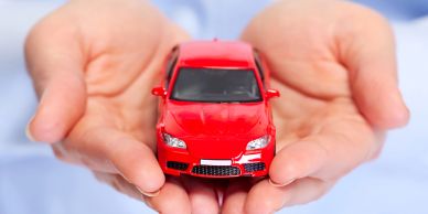 Hands holding a small red toy car.