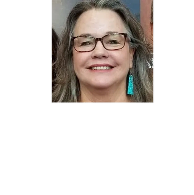 Smiling woman with glasses and turquoise earrings.