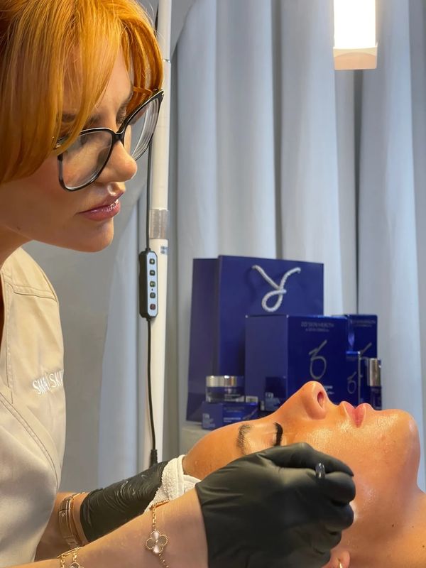 A beautician performing a facial treatment on a client.