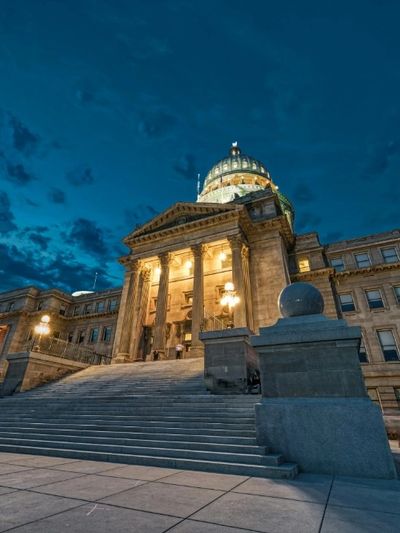 Illuminated historic capitol building at dusk with dramatic sky.