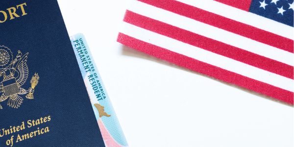 Passaporte dos EUA e cartão de residente permanente ao lado da bandeira americana.