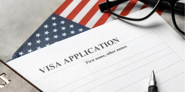 Formulário de pedido de visto com bandeira americana e óculos.