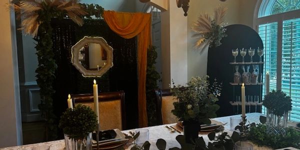 Elegant dining table setup with candles, greenery, and decorative mirror.