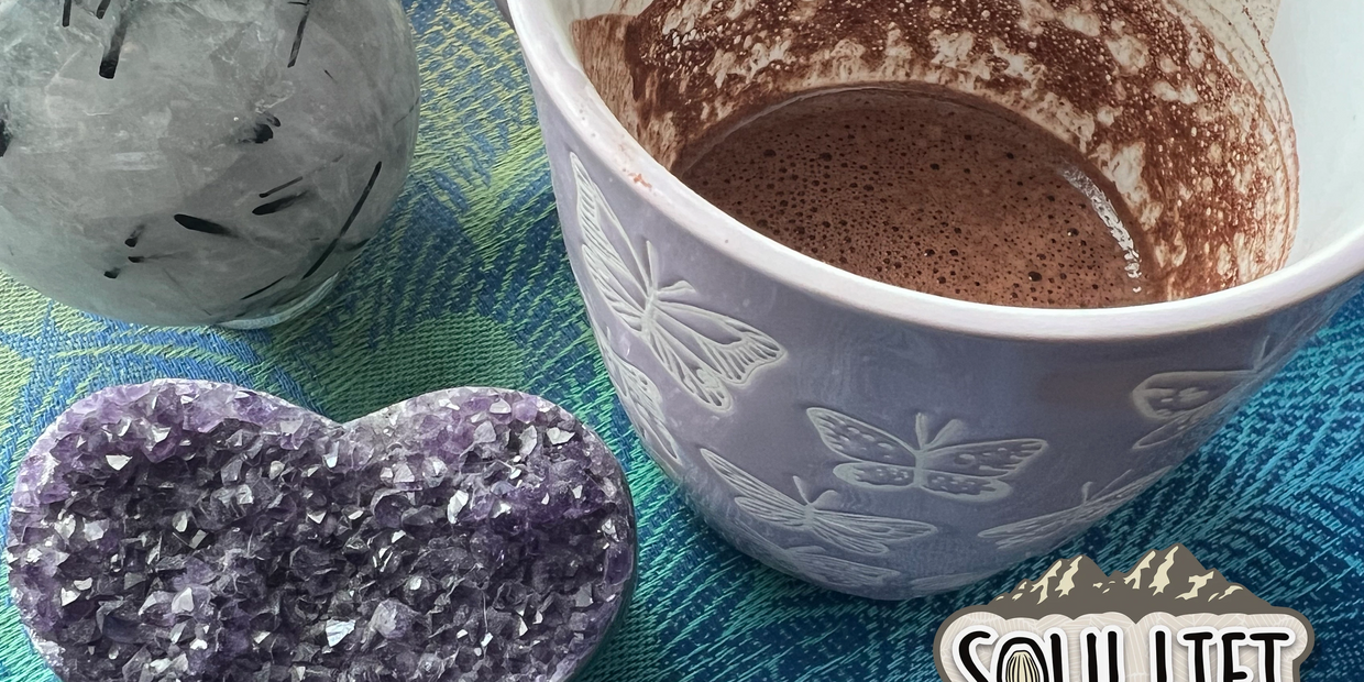 Ceremonial cacao cup with amethyst heart crystal and Soul Lift Cacao products on colorful cloth