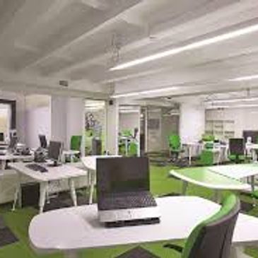 Modern open-plan office with green and white decor and multiple workstations.