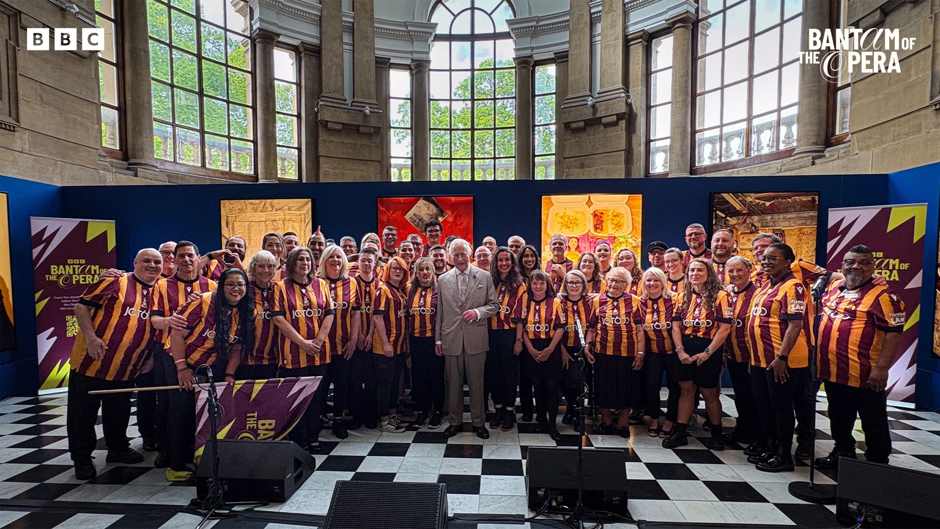 Large group wearing maroon and yellow striped shirts posing indoors with a man in a suit.