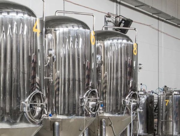 Large stainless steel fermentation tanks in a brewery or industrial facility.