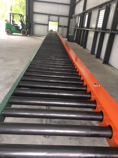Long conveyor belt in a warehouse with a parked forklift in the background