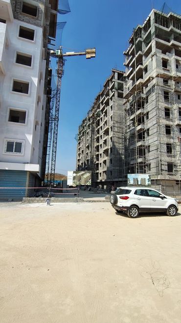 Construction site with multi-story buildings and a white car parked.