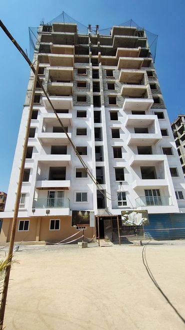 Unfinished multi-story residential building under clear blue sky.