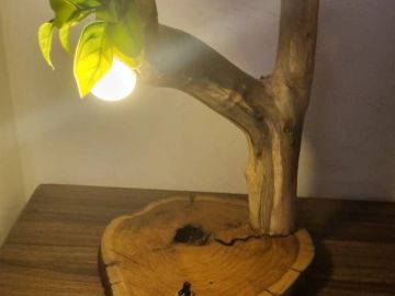 Lamp shaped like a tree branch with leaves and light bulb.