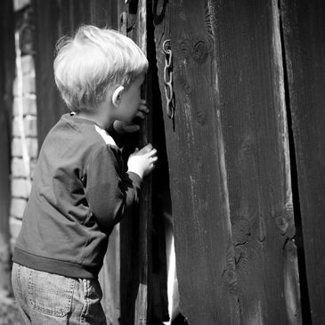 A child peeking through a wooden gate. Explore and discover