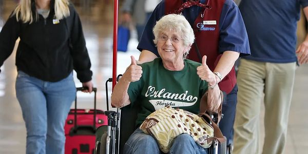 Wheelchair user showing thumbs up, smiling and happy she’s getting picked up from Airport for cruise