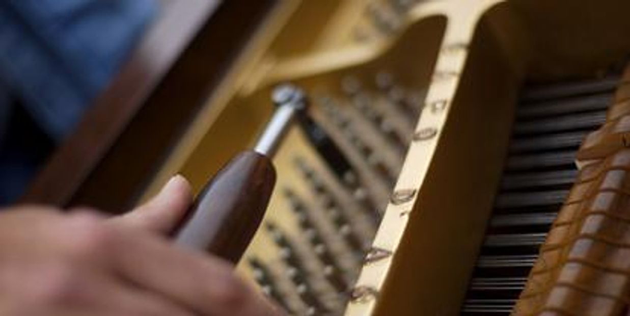 Hand tuning piano strings with a tuning lever.