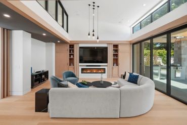 Modern living room with curved sofa, fireplace, and large glass doors.
