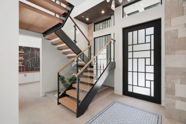 Modern staircase with glass railings in a bright entryway.